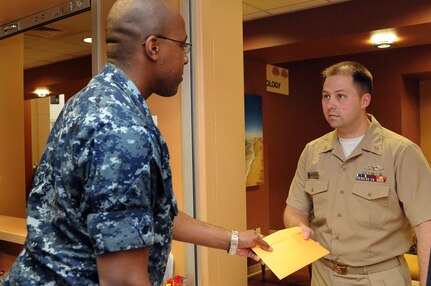 Petty Officer 2nd Class Japheth Tillman hands Chief Petty Officer Mark Harris a envelope containing images of Harris’s x-ray images. Once X-rays, Magnetic Resonance Imaging or any other examination has been reviewed and findings are reported, the images are burned to a CD for a patient to pick up to get the images to the requesting doctor who may be located out in town. Tillman is a hospital corpsman assigned to Naval Health Clinic Charleston and Harris is a machinist’s mate assigned to Navy Nuclear Power Training Unit as an instructor at Joint Base Charleston – Weapons Station. (U.S. Navy photo/Petty Officer 1st Class Jennifer Hudson)