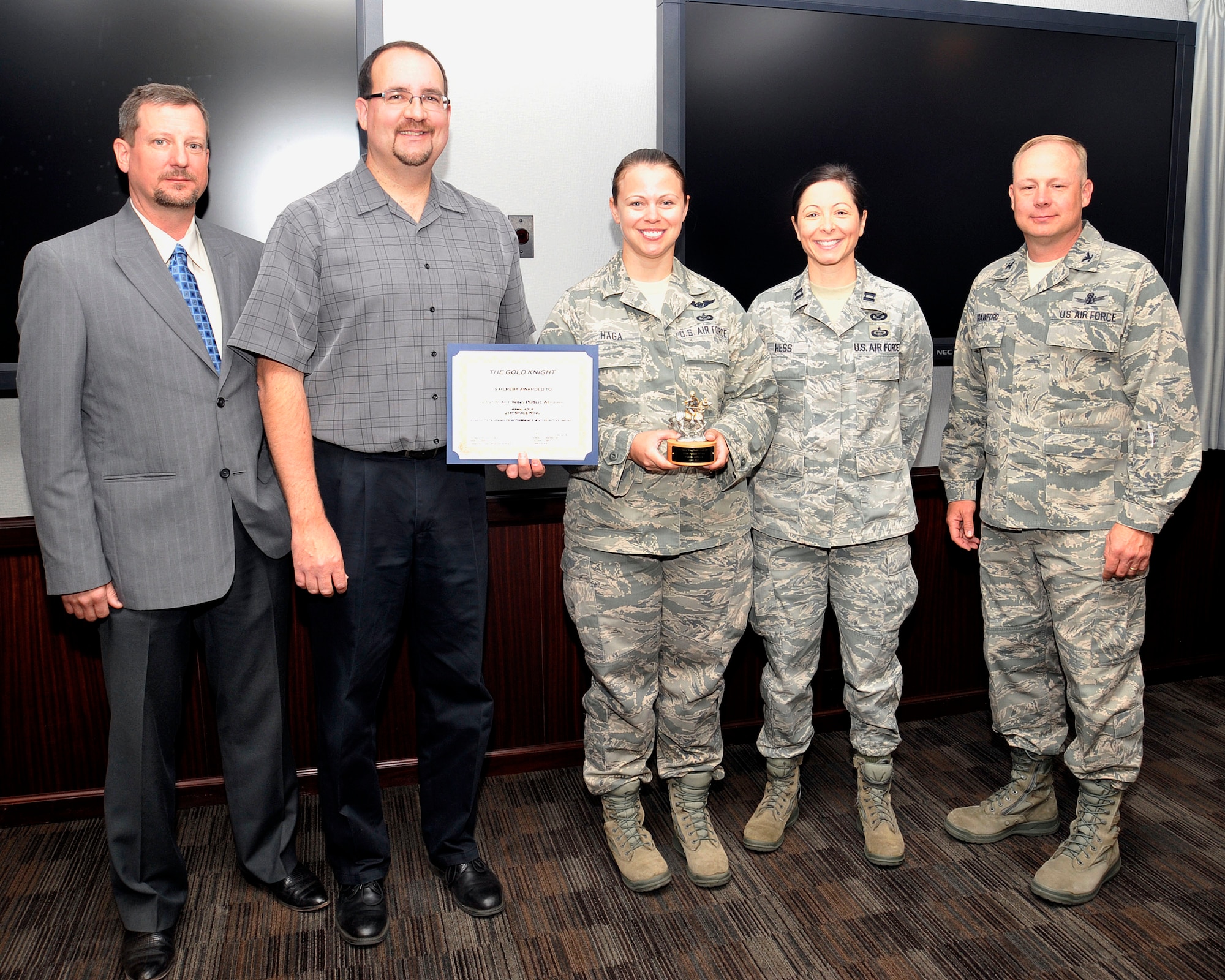 Col. Chris Crawford (right), 21st Space Wing commander, presented the Gold Knight Award to the 21st Space Wing Public Affairs Office May 30, for its work responding to media during an escaped inmate incident near Woodland Park, Colo. Accepting the award (left to right) are Public Affairs members Jeff Bohn, Stephen Brady, Staff Sgt. Stacey Haga and Capt. Holly Hess. Team members not pictured include Tech. Sgt. Amanda Callahan, Tech. Sgt. Kurt Arkenberg and Eileen Lopez. (U.S. Air Force photo/Dennis Howk)