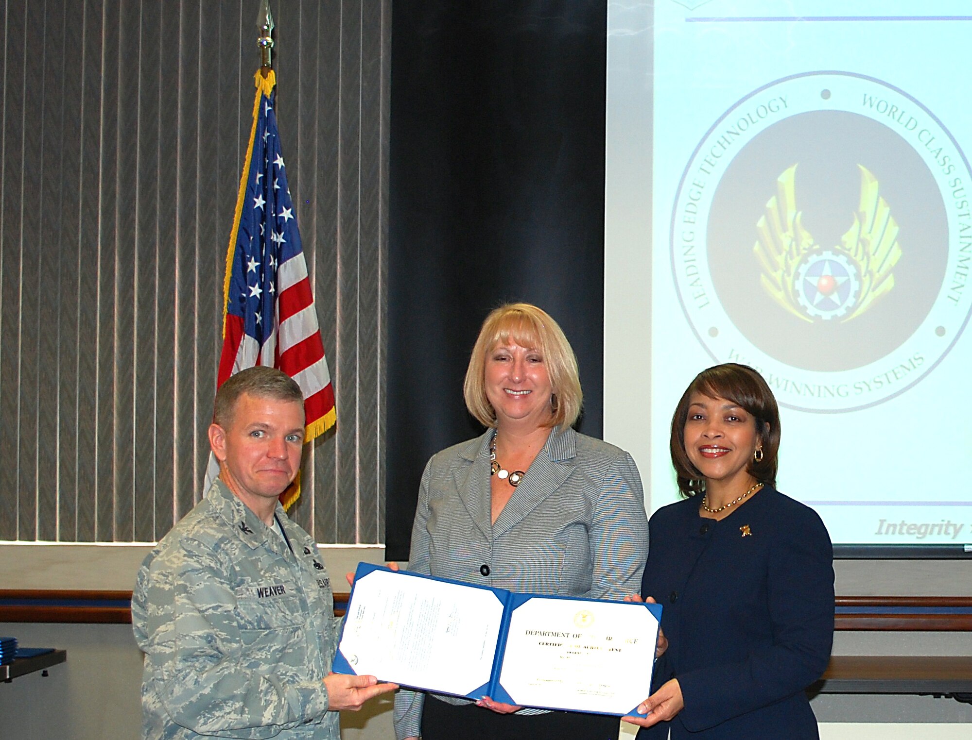 Michele Chebahtah (center) receives her Professional Maintenance Certification Level 1 Certificate from Col. Robert Weaver, 412th Maintenance Group commander,  and Sandra Wimberley, the program's Integrated Process Team leader. A data call is anticipated to occur in July. Civilian members serving in MX positions will have the opportunity to submit applications for professional certifications to the Training Division. The data call which is anticipated to run for a 45-day period. (Courtesy photo)