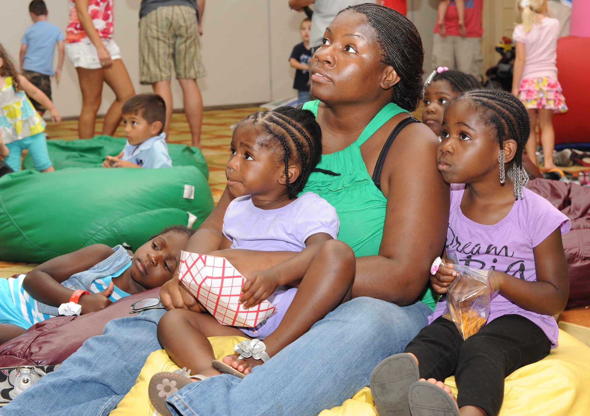 Sarah Harris, wife of Staff Sgt. Jeremy Harris, 801st Special Operations Aircraft Maintenance Squadron, watches a film along with her three children Akhia, 6, left, Ava, 2, center, and Adaija, 4, right, during the Family Night Out at the Soundside Club at Hurlburt Field, Fla., June 9, 2012. Attendees were able to view films on two different screens in the play and dining areas. (U.S. Air Force photo / Senior Airman Joe McFadden)(RELEASED)