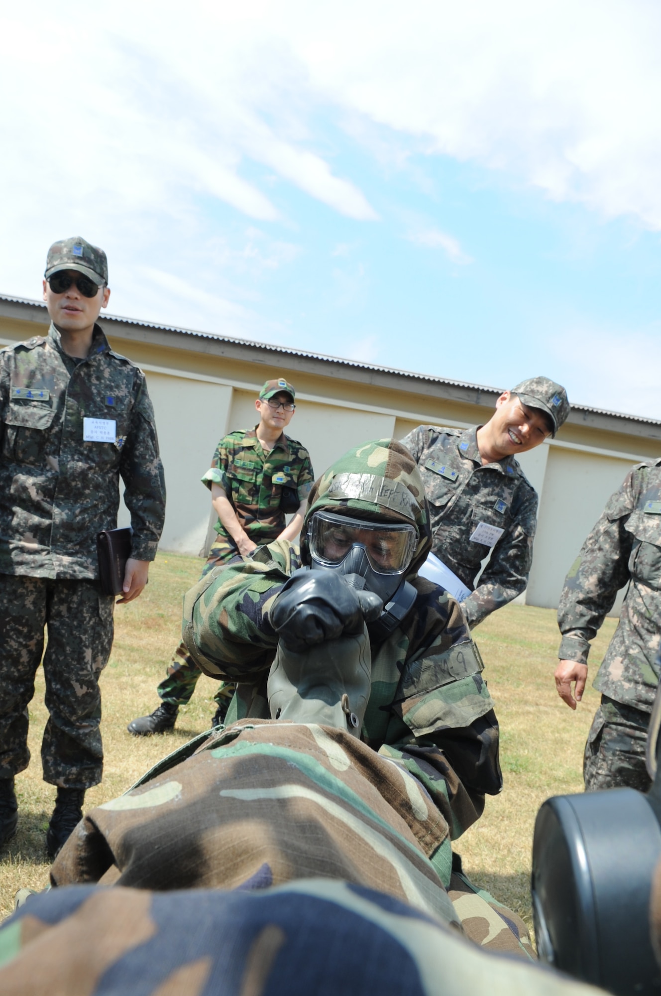 Master Sgt. Jeffrey Randall, 8th Civil Engineer Squadron emergency management flight superintendent, removes a wingman’s overboots as Republic of Korea Air Force members watch June 8, 2012, at Kunsan Air Base, Republic of Korea. The joint training provides familiarization for both sides on how each other operates in case of a chemical, biological, radiological or nuclear attack. (U.S. Air Force photo/Senior Airman Brigitte N. Brantley)