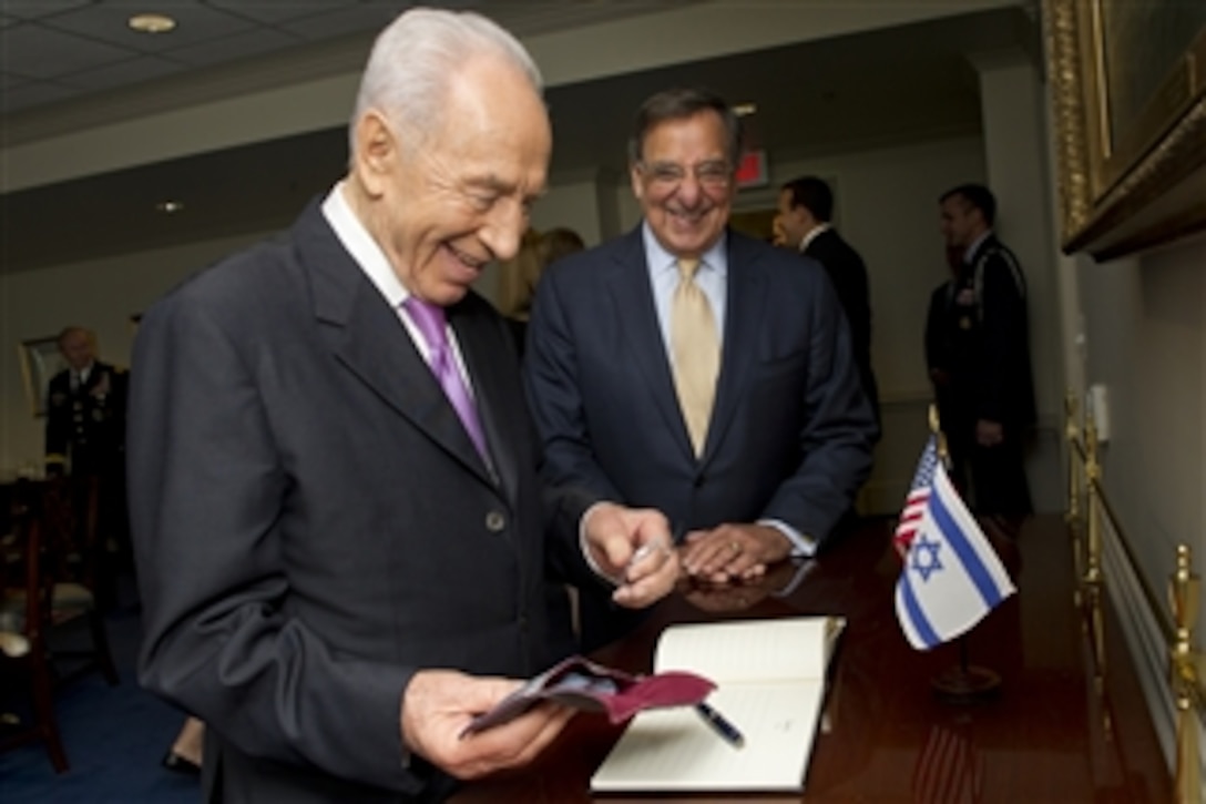 Israel's President Shimon Peres prepares to the sign the guest book of Secretary of Defense Leon E. Panetta in the Pentagon on June 11, 2012.  Peres, Panetta, and their senior advisors will meet to discuss security issues and the strong relationship between the United States and Israel.  