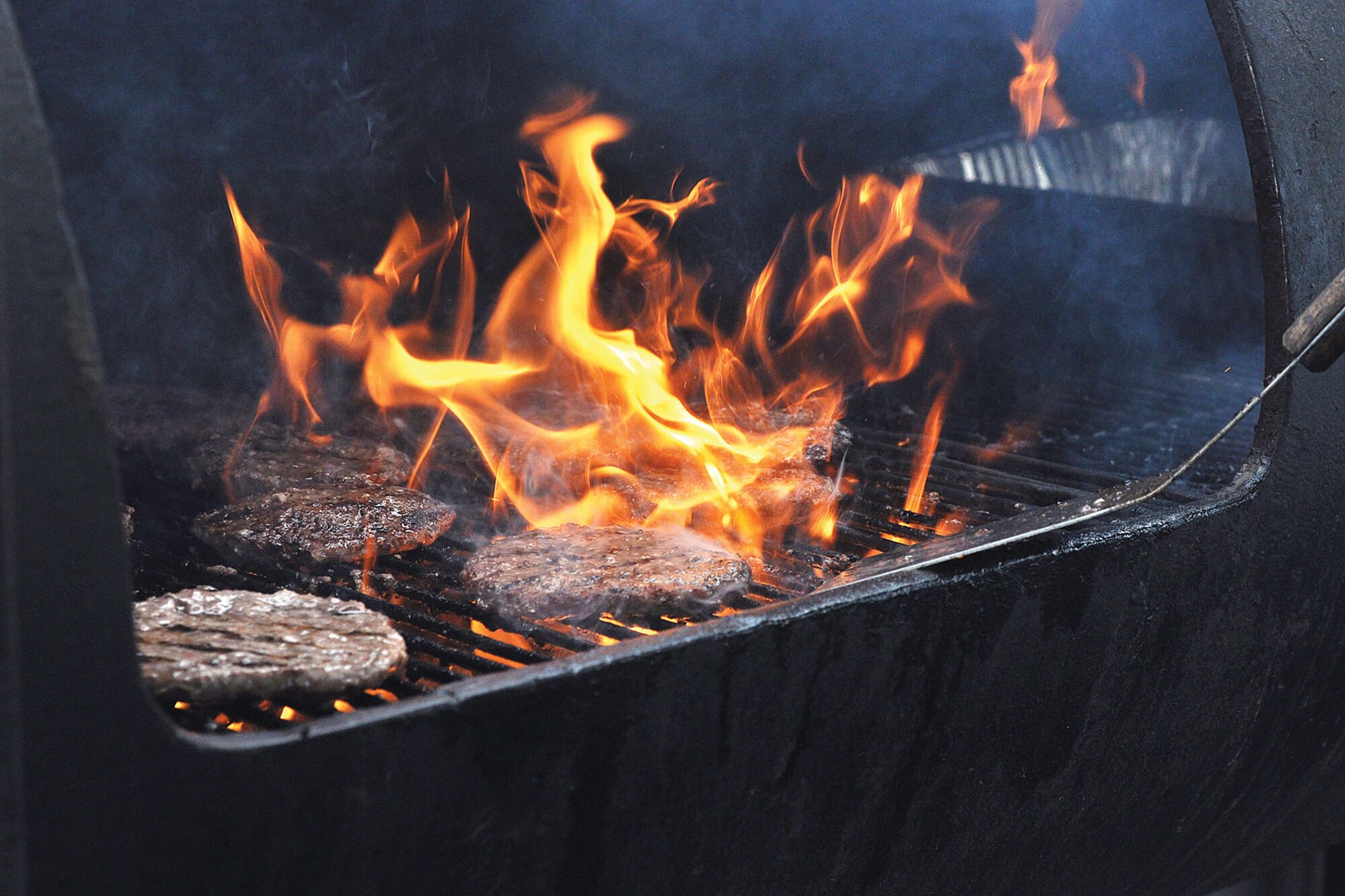 A volunteer flips hamburgers at Buckner Physical Fitness Center June 8 as part of the Anchorage Chamber of Commerce's annual Military Appreciation Picnic. (U.S. Air Force photo/John Pennell)