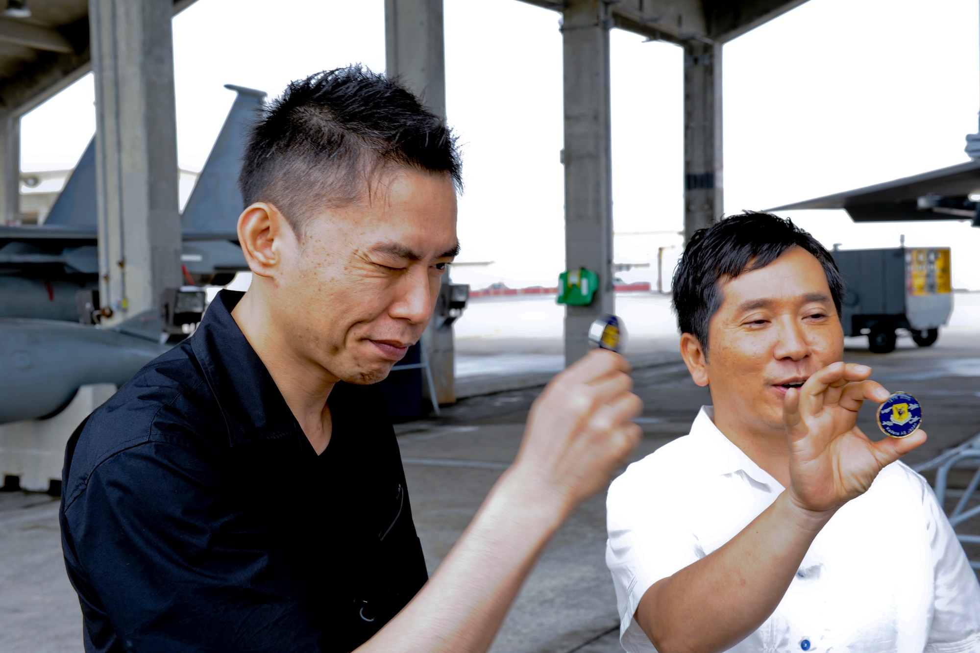 Hikari Ota (left) and Yuji Tanaka (right), hosts of the Japanese show Tanken Bakumon (Deep Inside), admire coins given to them by the 18th Wing Commander, Brig. Gen. Matthew Molloy, on Kadena Air Base, Japan, June 1, 2012. The comedic duo came to Kadena to film the latest episode of their new show that focuses on unique and limited-access locations. Kadena's segment is scheduled to air on the NHK channel June 20 beginning at 10 p.m. (U.S. Air Force photo/Airman 1st Class Brooke P. Beers)