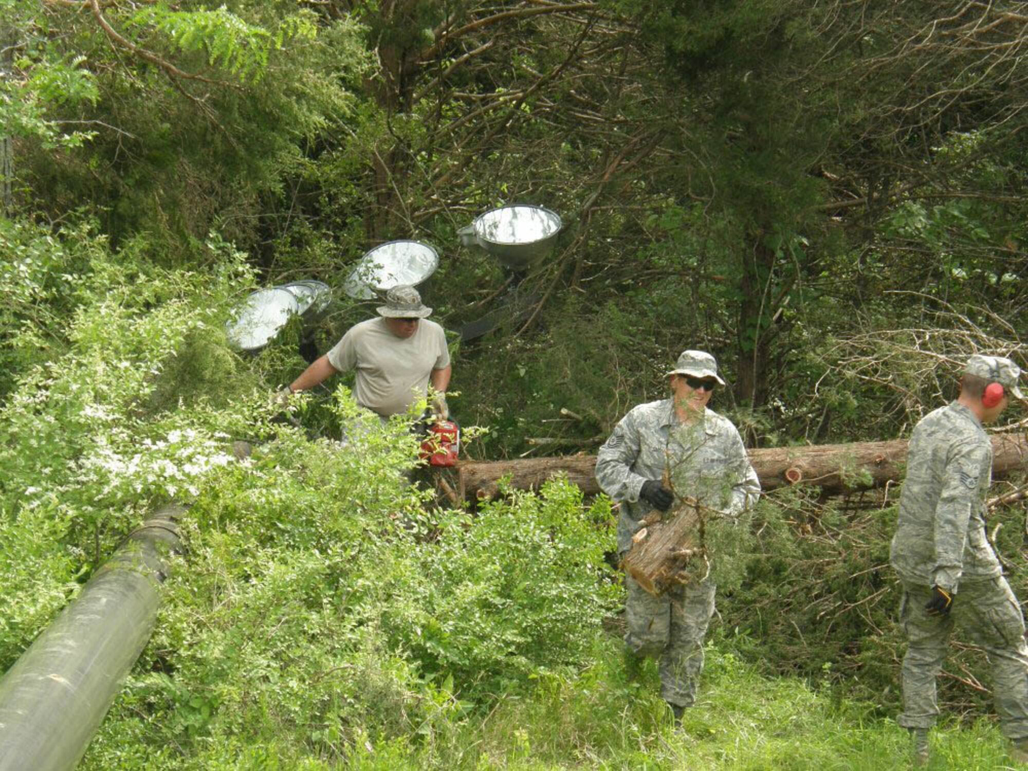 Airmen clear trees near a downed stadium light on the campus of Riverside Christian Academy. (Courtesy Photo) 