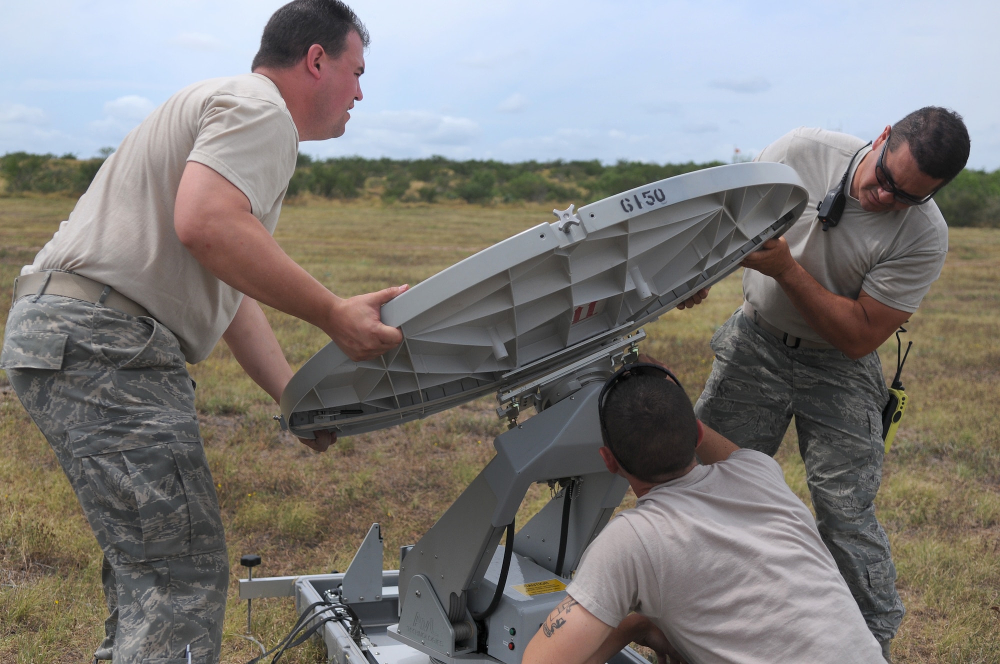 Master Sgt. David Nickell, a technician with Detachment 1, assists Staff Sgts. Joshua Cash (left) and Joseph Dawson (right), members of the 149th Communications Flight, both subcomponents of the Texas Air National Guard's 149th Fighter Wing, install a TRACSTAR satellite uplink device, which provided mobile communications for the Texas Red Flag exercise at Yankee Range, in McMullen County, on June 1, 2012. (Air National Guard photo by Senior Master Sgt. Mike Arellano / Released)