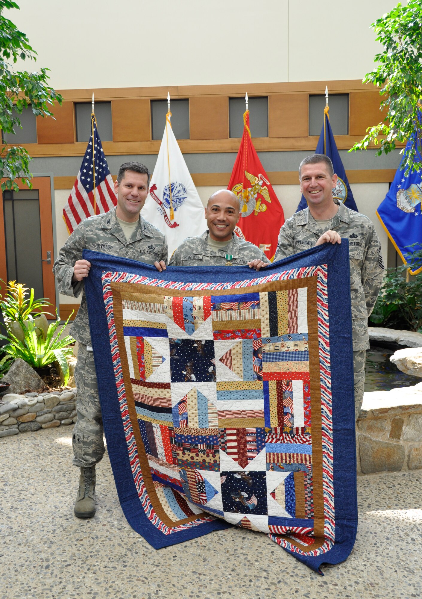 Army Staff Sgt. Luis Burgos (center) poses with Air Force Col. John M. Devilier, Air Force Mortuary Affairs Operations commander and Senior Master Sgt. Sean Applegate, AFMAO chief enlisted manager. Burgos was presented a Quilt of Valor on behalf of the Quilt of Valor Foundation for his service at the Charles C. Carson Center for Mortuary Affairs in a ceremony May 17, 2012. Burgos served as part of the Army Liaison Team as a member of the Casualty and Mortuary Affairs Operations Center, U.S. Army Human Resources Command, located at Fort Knox, Ky. He was also awarded the Army Commendation Medal. (U.S. Air Force photo/Christin Michaud)

