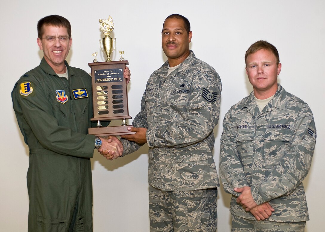Col. Steven Hiss, 28th Bomb Wing vice commander, congratulates Tech. Sgt. Michael Eames, 28th Maintenance Operations Squadron, and Senior Airman Evan McPhail, 28th Maintenance Squadron, for winning the Rapid City Area Chamber of Commerce Golf Tournament Patriot Cup during the 28th BW production meeting at Ellsworth Air Force Base, S.D., June 13, 2012. A team of four Airmen from Ellsworth consisting of Eames, McPhail, Maj. Joseph Reidy, 37th Bomb Squadron, and Airman 1st Class Casey Reed, 28th Civil Engineer Squadron, participated in the tournament on June 11, 2012 and took top honors. Each year a team from Ellsworth and the South Dakota National Guard compete in the tournament in the hopes of winning the military trophy. (U.S. Air Force photo by Staff Sgt. Marc I. Lane/Released)