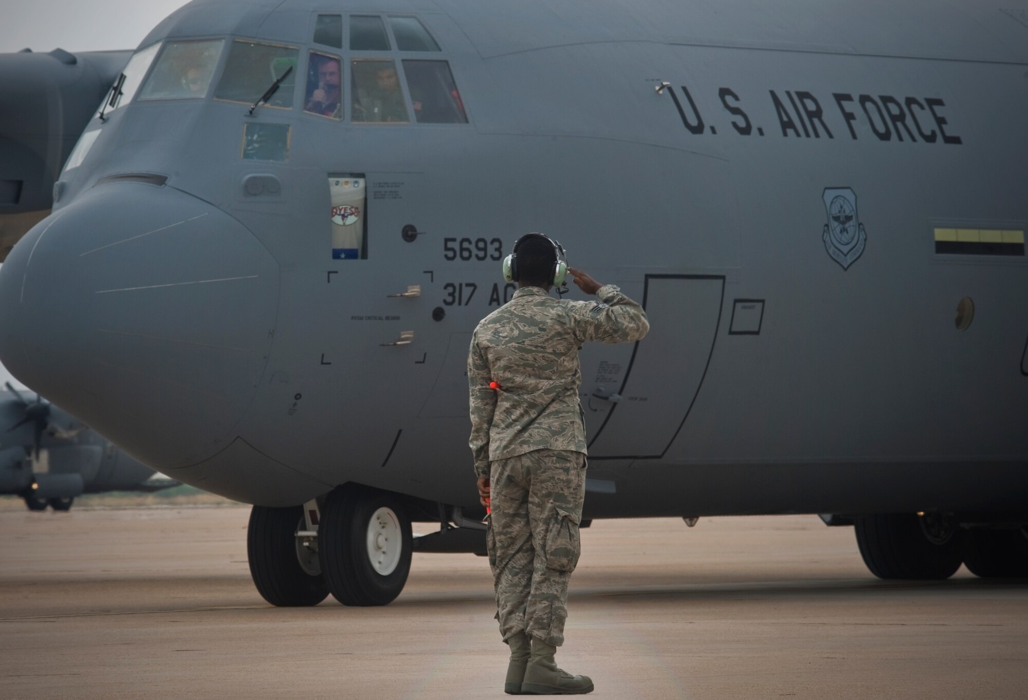 An Airman from the 317th Airlift Group salutes the arriving C-130 J-model June 12, 2012, at Dyess Air Force Base, Texas. The aircraft is the 20th of 28 J-models to be delivered to Dyess by 2013, replacing the current legacy fleet of C-130 H-models. (U.S. Air Force photo by Airman 1st Class Jonathan Stefanko/ Released)
