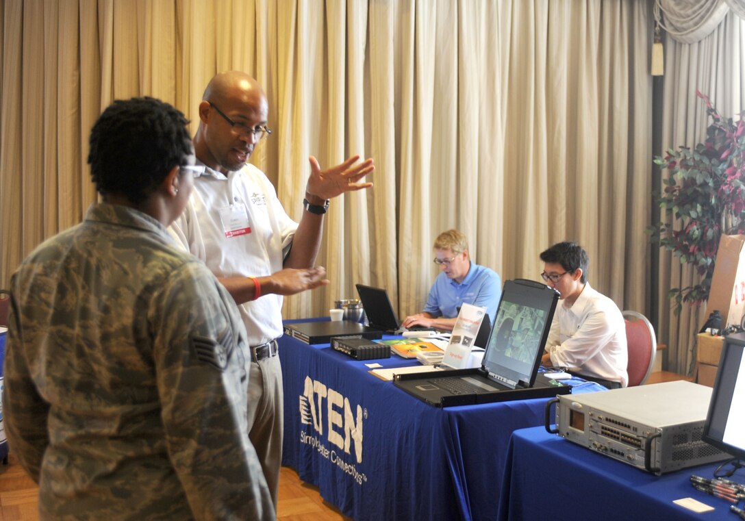 Corey Piggott, center, a Spirent Federal Systems vendor, explains new improvements in Global Positioning System technology at the Langley Club, Langley Air Force Base, Va., June 12. The semi-annual Air Combat Command Technology Expo featured 30 vendors displaying products such as communications and visual technologies. The expo brings together General Services Administration industry leaders and military personnel in order to keep Langley AFB up-to-date on emergent products. (U.S. Air Force photo by Airman 1st Class Austin C. Harvill) 120612-F-XD389-003