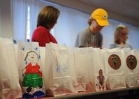 MINOT AIR FORCE BASE, N.D. -- Members of the Minot Officers’ Spouses’ Club fill hundreds of paper bags decorated by Team Minot children during the annual Airman’s Cookie Drive during the wintertime. In addition to the scholarship program and charitable donations the spouses group is also responsible for coordinating this drive. During the event, more than 10,000 cookies from the local community, including residents of the city of Minot, are gathered, gift wrapped and distributed to over one thousand single Airmen in the dormitories who are unable to be with their families during the holiday season. (U.S. Air Force photo/Senior Airman Ashley N. Avecilla)