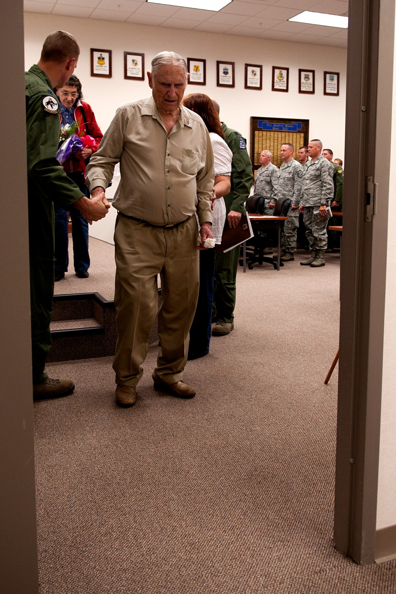 U.S. Air Force Lt. Col. Heath Wharton, the 11th Bomb Squadron commander, helps Claude McCrocklin following a Room Dedication ceremony, while attendees sing the Air Force song, Barksdale Air Force Base, La., June 1, 2012. The 11th BS dedicated a conference room in honor of McCrocklin for his service and sacrifice as a B-24 Liberator bombardier during World War II. (U.S. Air Force photo by Master Sgt. Greg Steele/Released)