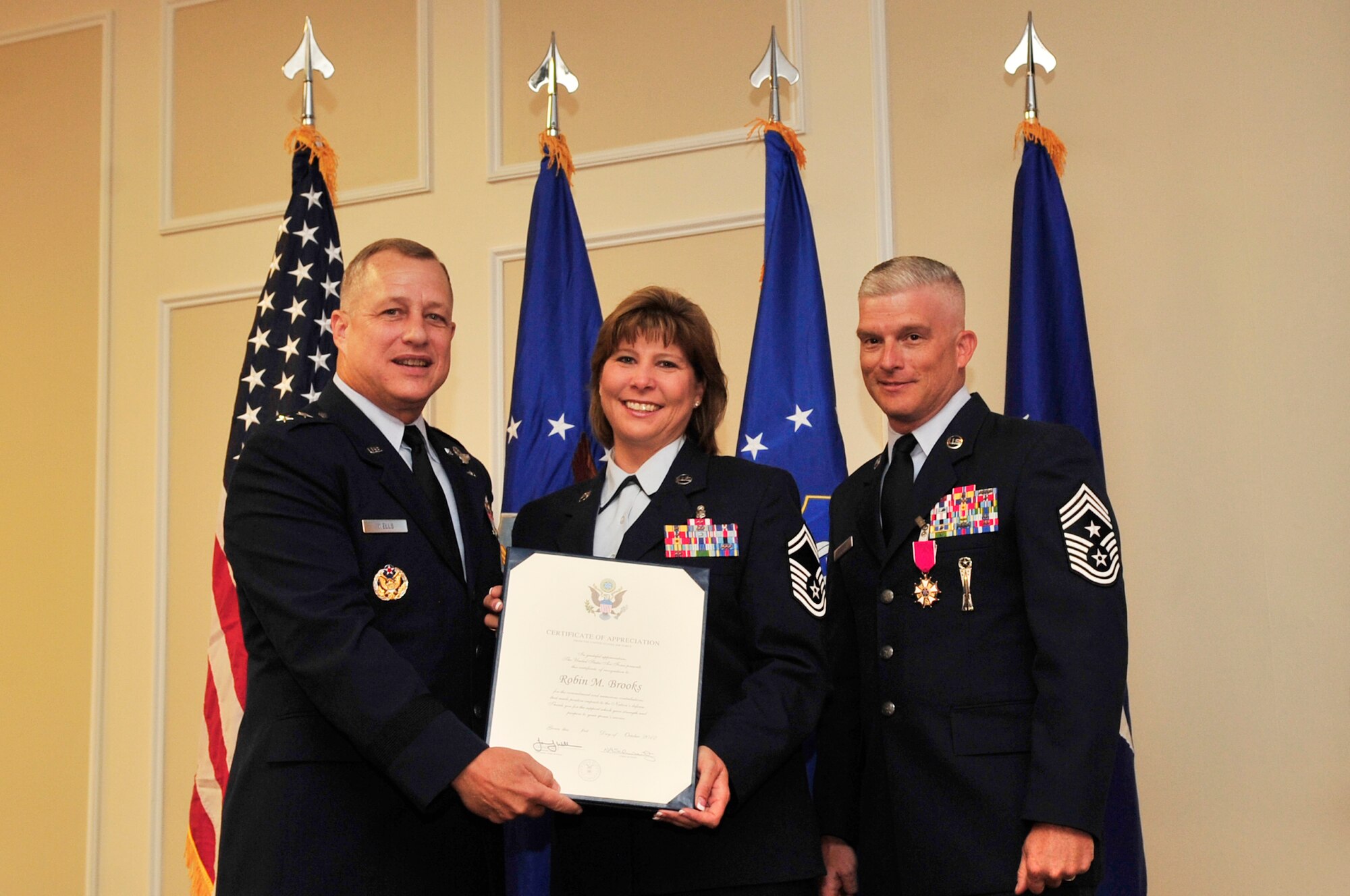 U.S. Air Force Senior Master Sgt. Robin Brooks, 20th Medical Support Squadron superintendent, receives a certificate of appreciation from Maj. Gen. Lawrence Wells, 9th Air Force commander, at a retirement ceremony for her husband Chief Master. Sgt. Robert Brooks, 9th Air Force command chief, at Shaw Air Force Base, S.C., June 8, 2012.  This certificate is given to family members to commend them for being the morale support when needed, and enduring difficult times with their Airmen.(U.S. Air Force photo by Airman Nicole Sikorski/Released)