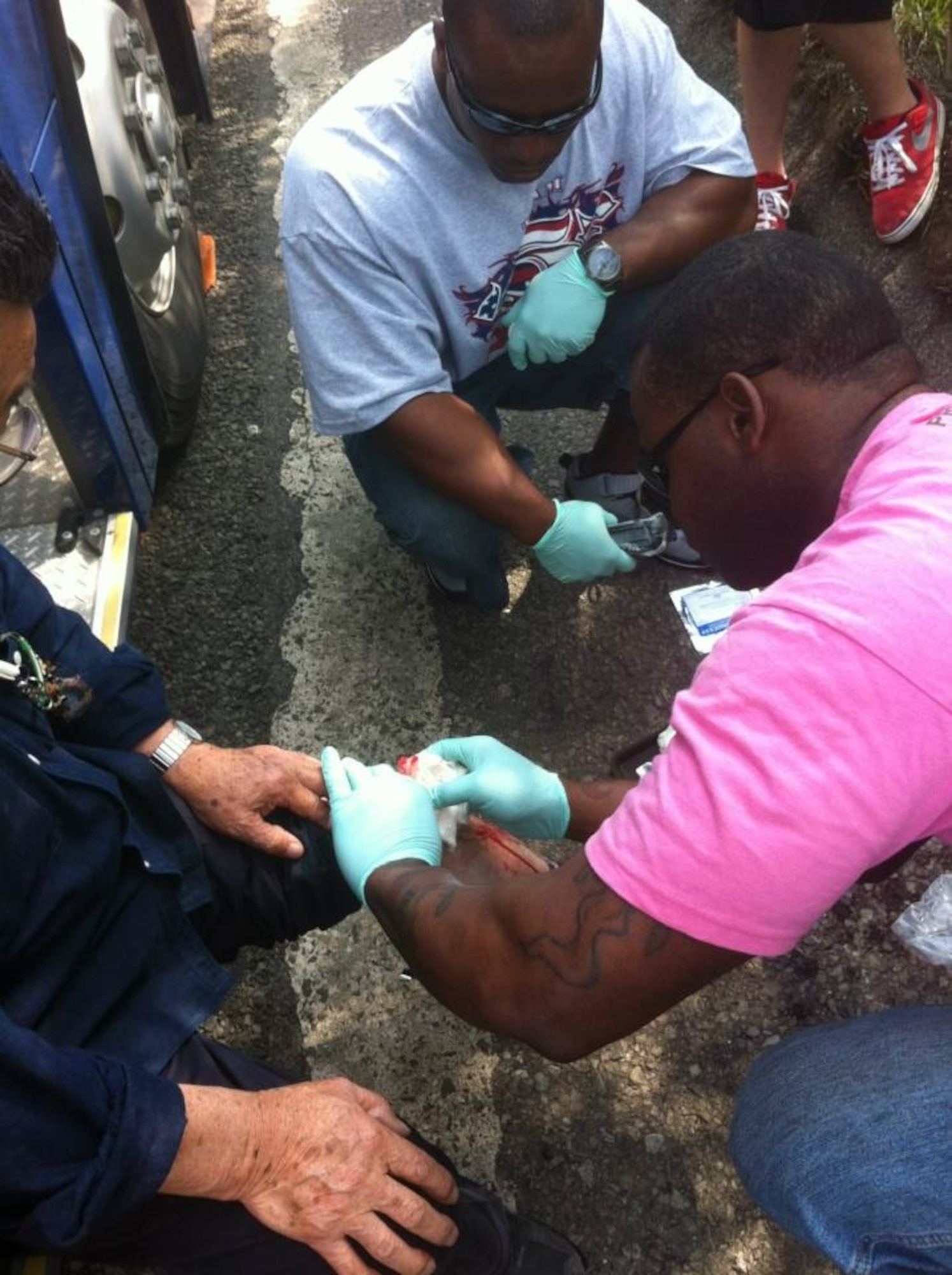 U.S. Air Force Staff Sgts. Justin James and Donald Jackson, 35th Logistics Readiness Squadron training section supervisors, bandage a driver’s leg after a major vehicle accident south of Sendai, Japan, June 7, 2012. A group of servicemembers put to use their hands-on training, such as self-aid buddy care and critical-life saving training, by bandaging the driver’s injured leg and keeping him alert. (Courtesy Photo/Released)