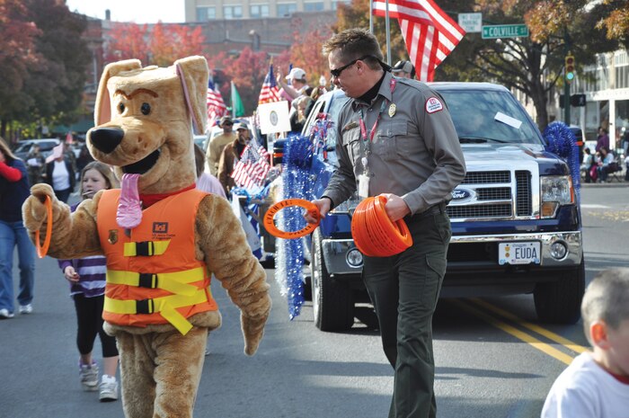 Bobber, the Corps' water safety dog and District Natural Resource Resource Speicalist Michael Swenson hand out frisbees during the Veteran's Day Parade on Main Street in Walla Walla, Wash. on Veteran's Day 2011.