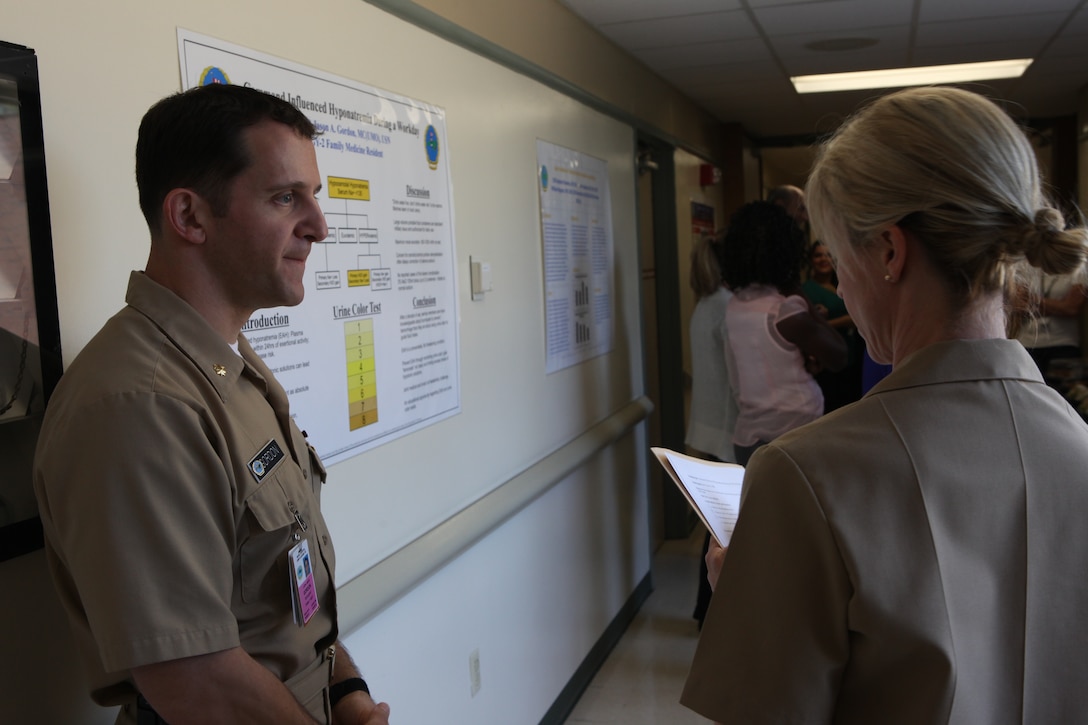 Cmdr. Stephanie Cole, director for research, talks with Lt. Cmdr. Jason A. Gordon about his research concerning over-hydration during Naval Hospital Camp Lejeune’s second annual Research Symposium aboard Marine Corps Base Camp Lejeune June 8. Residents had been doing research and testing for as much as two years and presented their findings at the symposium.