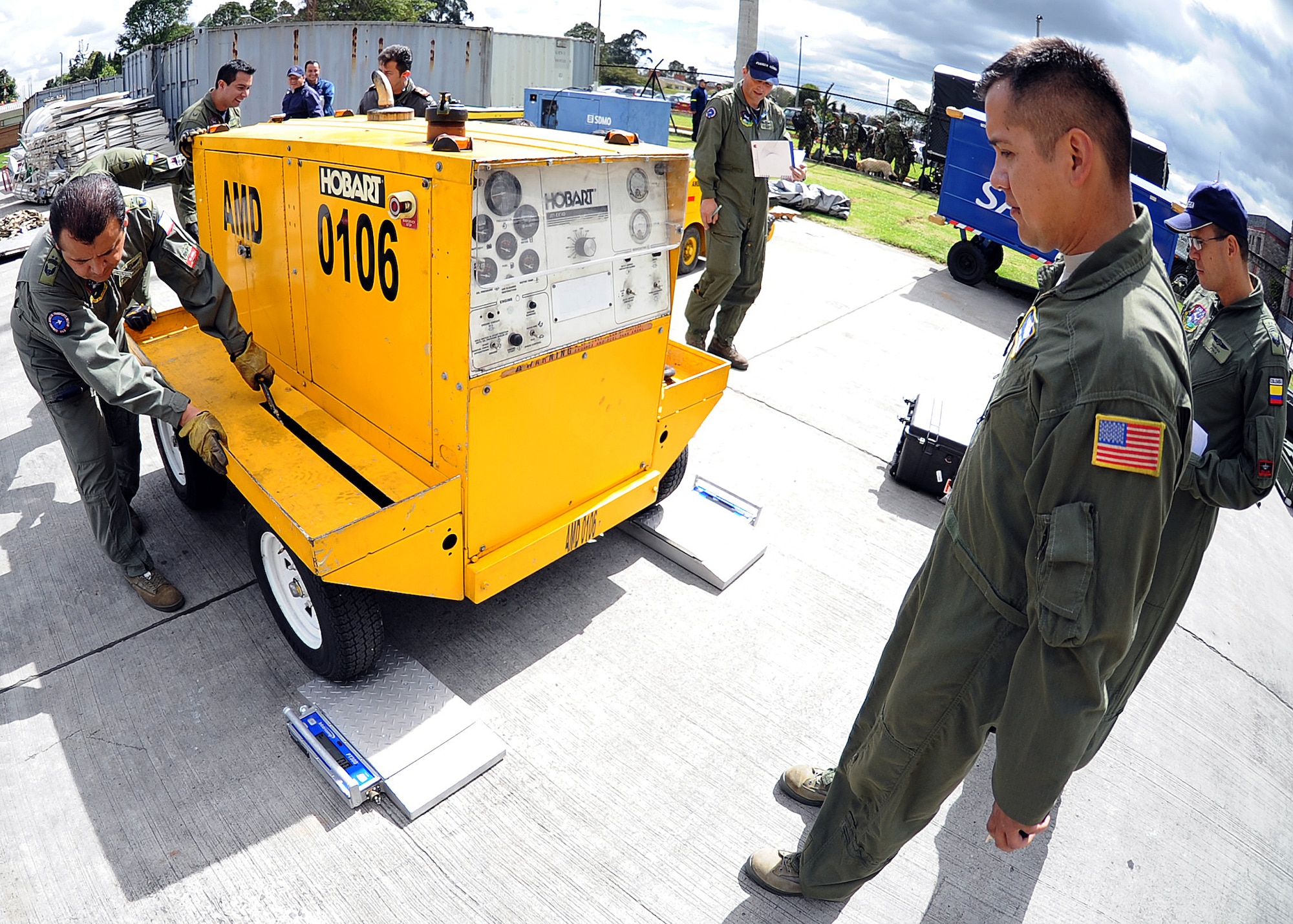 Staff Sgt. Jorge Borges, 571st Mobility Support Advisory Squadron loadmaster, looks on as members of the Colombian air force roll a generator on to two portable scales to calculate the center of balance of the generator during the hands on pallet build-up seminar June 6 at Commando Aéreo de Transporte Militar, Bogota, Colombia.  (U.S. Air Force photo by Tech. Sgt. Lesley Waters)