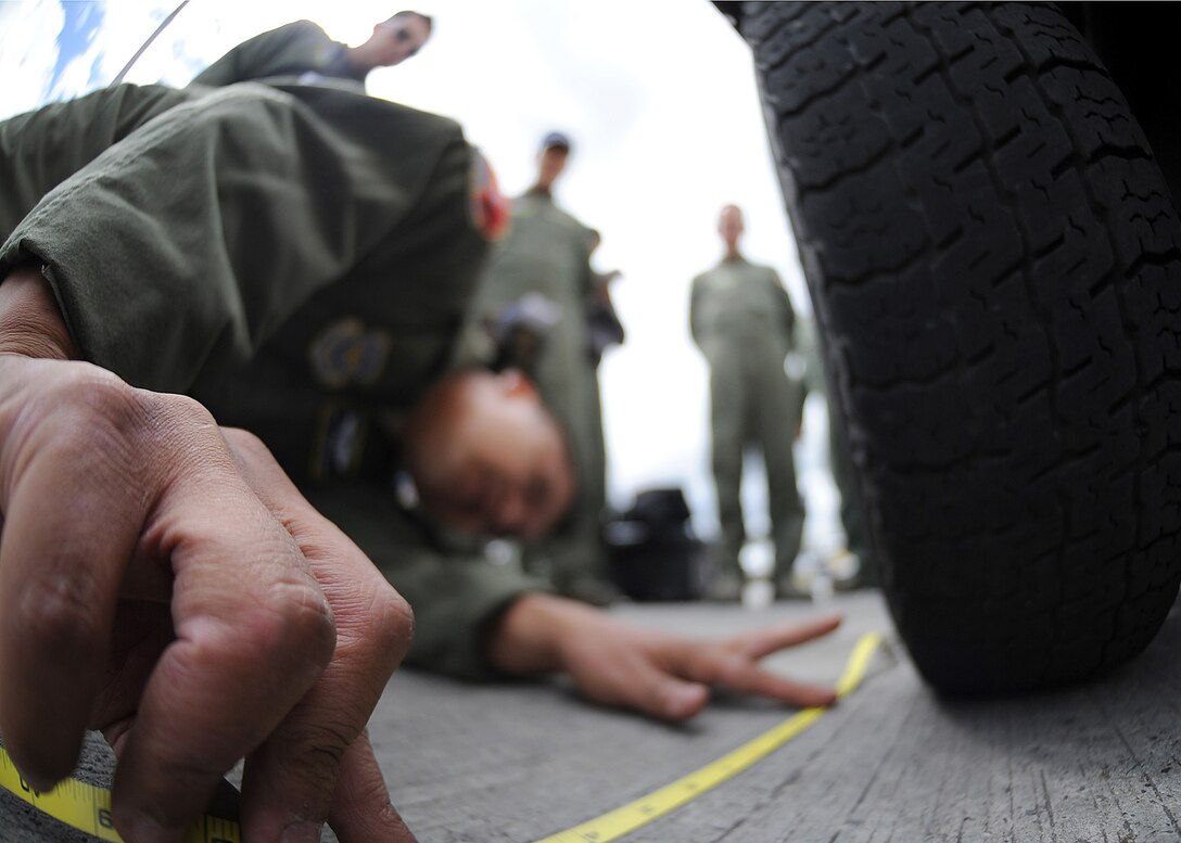 Staff Sgt. Jorge Borges, 571st Mobility Support Advisory Squadron loadmaster, measures the foot print of the front tire during the cargo build up seminar June 6 at Commando Aéreo de Transporte Militar, Bogota, Colombia.  The foot print is to calculate the PSI of the generator.  (U.S. Air Force photo by Tech. Sgt. Lesley Waters)