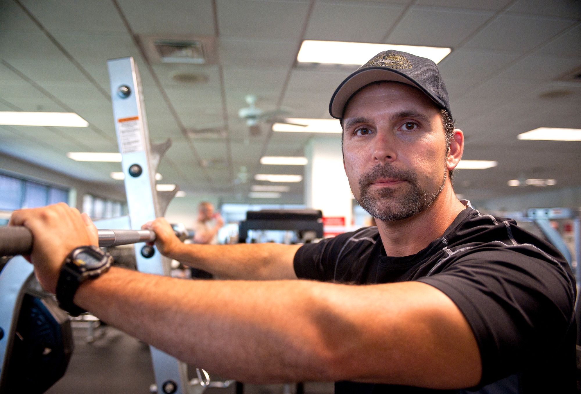Chris Andruschkevich, Aerobics and Fitness Association of America certified personal trainer, poses for a photo next to a squat rack at the Freedom I Fitness Center at Moody Air Force Base, Ga., June 13, 2012. Andruschkevich typically starts work at the fitness center around 5 a.m., and stays until 8 p.m., most days. (U.S. Air Force photo by Airman 1st Class Jarrod Grammel/Released)
