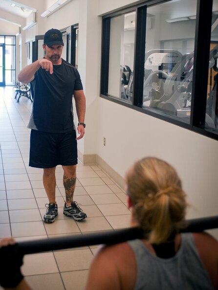 Chris Andruschkevich, Aerobics and Fitness Association of America certified personal trainer, signals for U.S. Air Force Staff Sgt. Jessica Carter, 23d Equipment Maintenance Squadron precision guided munitions crew chief, to continue performing squats during a training session at the Freedom I Fitness Center at Moody Air Force Base, Ga., June 13, 2012. Andruschkevich’s interest in personal training began while he was in high school after a summer job at Joe Weider’s Bodybuilding Camp. (U.S. Air Force photo by Airman 1st Class Jarrod Grammel/Released)
