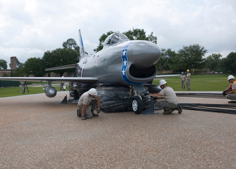 Members of the 23d Equipment Maintenance Squadron and the 23d Civil Engineer Squadron work together to lift an F-86L Sabre to be mounted at the President George W. Bush Air Park at Moody Field June 12, 2012, at Moody Air Force Base, Ga. The F-86 was moved from downtown Valdosta, Ga., where it was known as a historic landmark, refurbished by Moody Airmen and displayed with other historic aircraft that have flown at Moody. (U.S. Air Force photo by Senior Airman Eileen Meier/Released)
