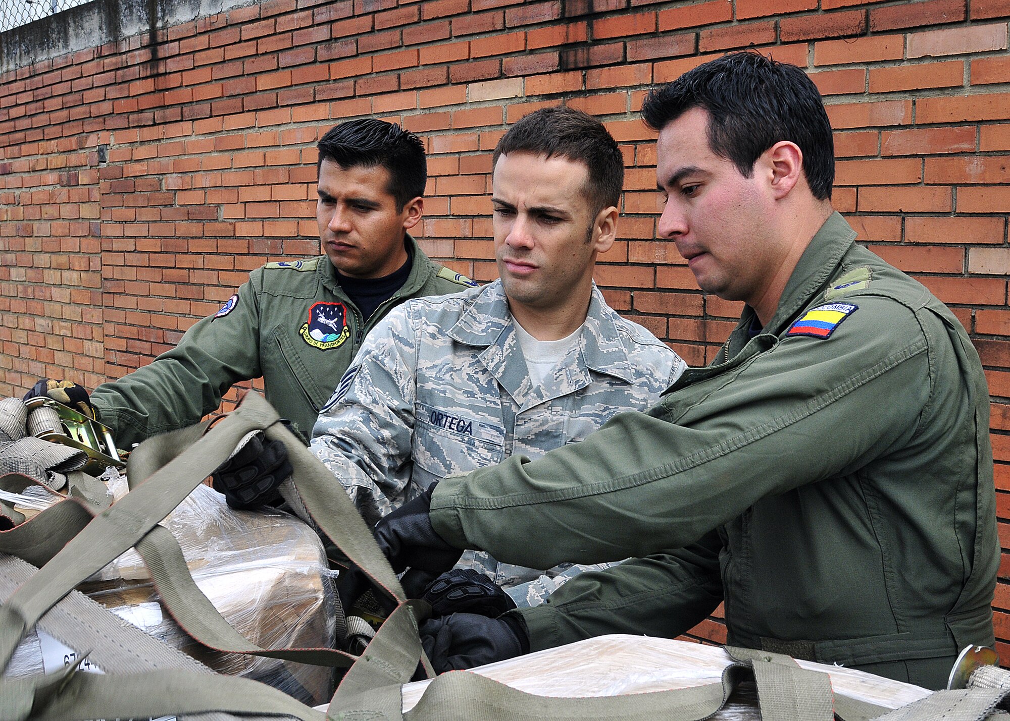 Staff Sgt. Angel Ortega, 571st Mobility Support Advisory Squadron air transportation air advisor, works with Técnico Cuarto Yefferson Oviedo and Tecnico Cuarto Cesar Gomez, Colombian air force members, on properly securing cargo during the pallet build-up seminar June 6 at Commando Aéreo de Transporte Militar, Bogota, Colombia.  (U.S. Air Force photo by Tech. Sgt. Lesley Waters)
