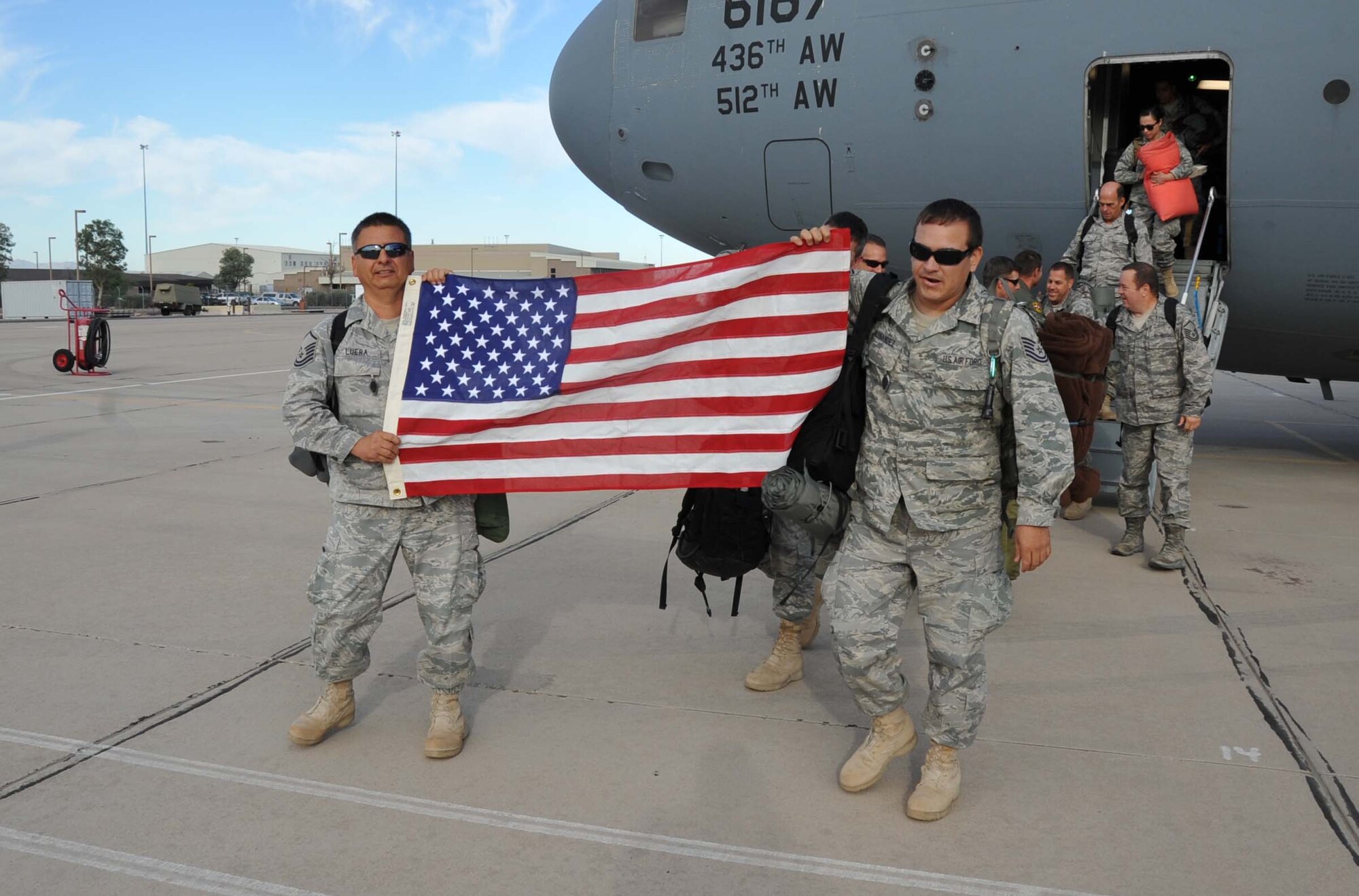 Master Sgt. Augstin Luera with the 943rd Maintenance Squadron and Tech. Sgt. Thomas Hernandez with the 305th Rescue Squadron hold up an American flag as they both depart a C-17 Globemaster III on the flight line at Davis Monthan Air Force Base, Ariz. More than 70 Reserve Airmen from the 943rd Rescue Group here returned home June 9 through the 19th after a four month deployment at Camp Bastion, Afghanistan providing medical evacuation capabilities in Afghanistan’s Regional Command Southwest. (U.S. Air Force Photo/ Master Sgt. Luke Johnson)