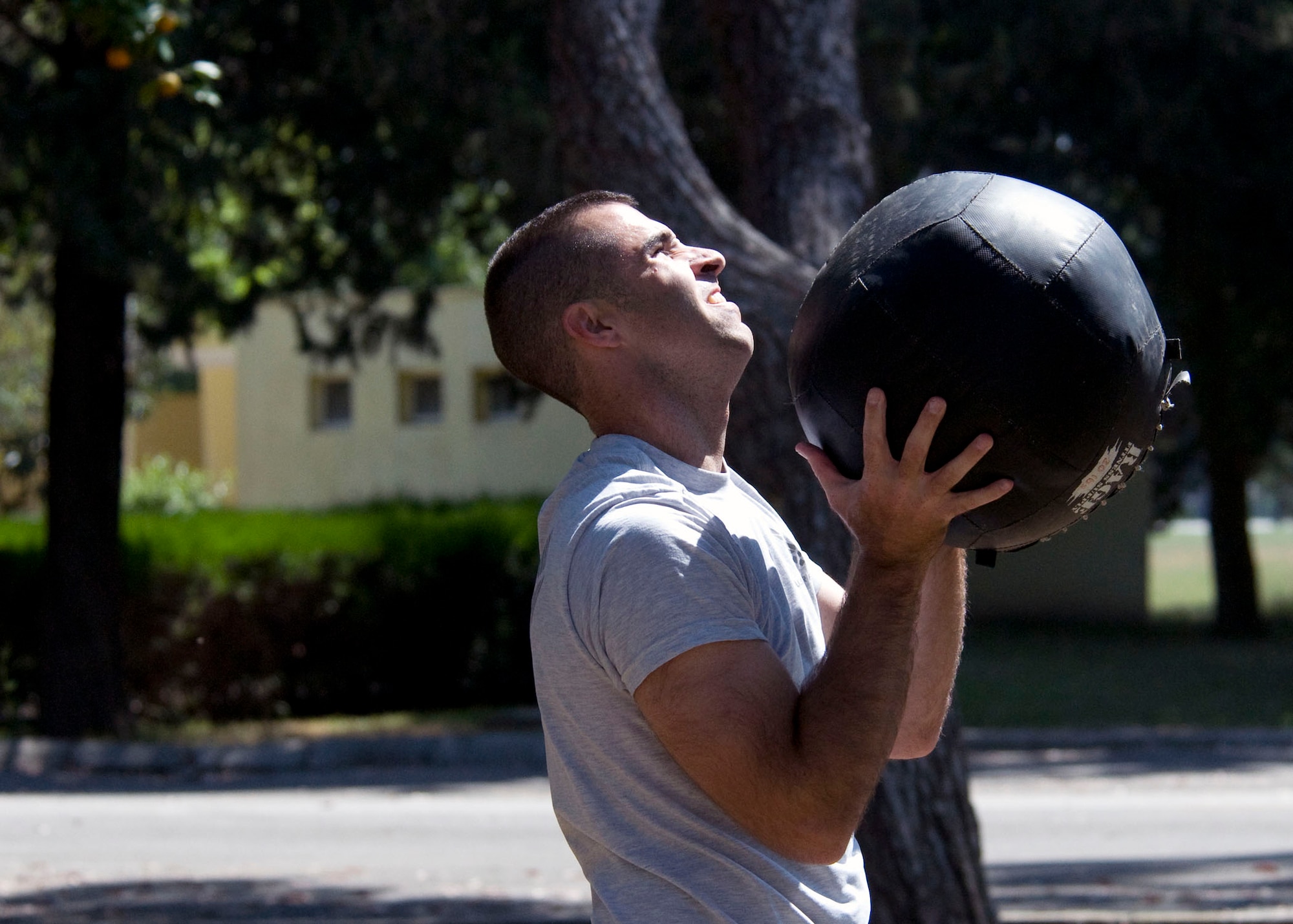 Ryan Stockbridge, 728th Air Mobility Squadron, catches a wall ball after tossing it against a tree during the 'Lik Fit Games June 8, 2012, at Incirlik Air Base, Turkey. The obstacle was part of the last event and included an overhead weight lift, squats, burpies and hanging leg lifts. (U.S. Air Force photo by Senior Airman Marissa Tucker/Released)