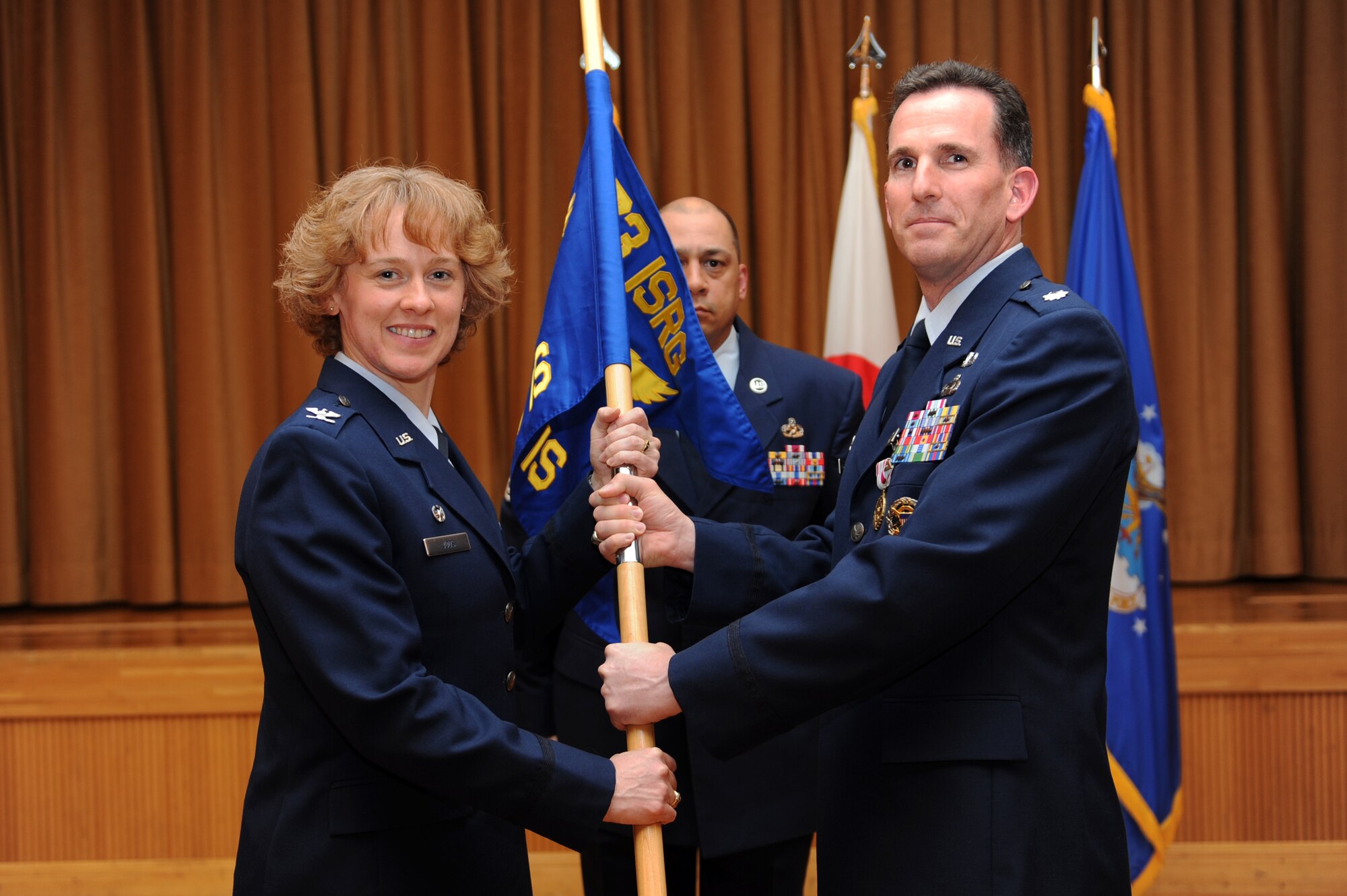 U.S. Air Force Col. Kimberlee Joos, left, 373rd Intelligence, Reconnaissance and Surveillance Group commander, relinquishes Lt. Col. Michael Smith of command of the 301st Intelligence Squadron during a change of command ceremony at Misawa Air Base, Japan, June 14, 2012. Smith is going on a one year deployment to Afghanistan. (U.S. Air Force photo by Airman 1st Class Kia Atkins/Released)