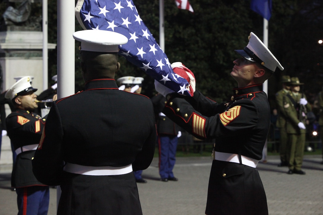 First Sergeant David A. McKinley, the Alpha Battery first sergeant with 1st Battalion, 11th Marine Regiment, retrieves the U.S. flag with Staff Sgt. James Jordan, an engineer section chief with Headquarters Battery, 11th Marine Regiment, during the sunset ceremony at the Parliament House here, June 14. McKinley, 37-year-old native of Cincinnati, presented the flag to Prime Minister of New Zealand John Key. Government and military officials of the United States and New Zealand commemorated the 70th anniversary of the arrival of U.S. forces in Wellington during World War II. Australian and New Zealand forces were conducting heavy fighting in Northern Africa in 1942 while U.S. forces played a significant role in the defense of Oceania.::r::::n::(U.S. Marine Corps photo by Cpl. Sarah B. Novotny)::r::::n::