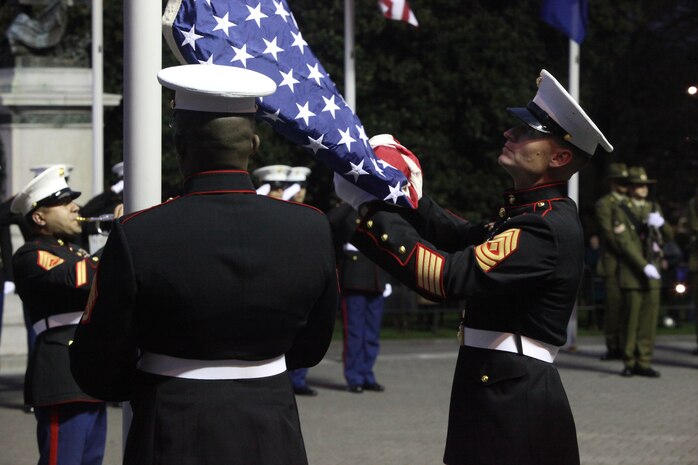 First Sergeant David A. McKinley, the Alpha Battery first sergeant with 1st Battalion, 11th Marine Regiment, retrieves the U.S. flag with Staff Sgt. James Jordan, an engineer section chief with Headquarters Battery, 11th Marine Regiment, during the sunset ceremony at the Parliament House here, June 14. McKinley, 37-year-old native of Cincinnati, presented the flag to Prime Minister of New Zealand John Key. Government and military officials of the United States and New Zealand commemorated the 70th anniversary of the arrival of U.S. forces in Wellington during World War II. Australian and New Zealand forces were conducting heavy fighting in Northern Africa in 1942 while U.S. forces played a significant role in the defense of Oceania.::r::::n::(U.S. Marine Corps photo by Cpl. Sarah B. Novotny)::r::::n::