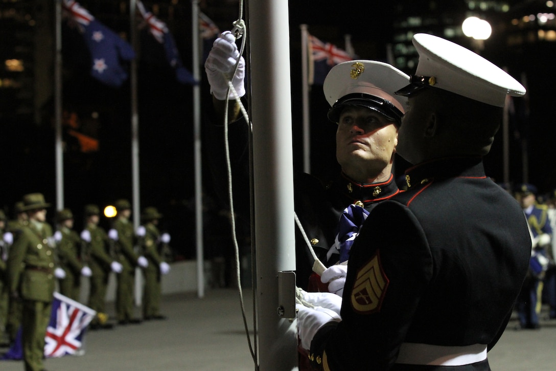 First Sergeant David A. McKinley, the Alpha Battery first sergeant with 1st Battalion, 11th Marine Regiment, retrieves the U.S. flag with Staff Sgt. James Jordan, an engineer section chief with Headquarters Battery, 11th Marine Regiment, during the sunset ceremony at the Parliament House here, June 14. McKinley, 37-year-old native of Cincinnati, presented the flag to Prime Minister of New Zealand John Key. Government and military officials of the United States and New Zealand commemorated the 70th anniversary of the arrival of U.S. forces in Wellington during World War II. Australian and New Zealand forces were conducting heavy fighting in Northern Africa in 1942 while U.S. forces played a significant role in the defense of Oceania.::r::::n::(U.S. Marine Corps photo by Sgt. Jacob H. Harrer)::r::::n::