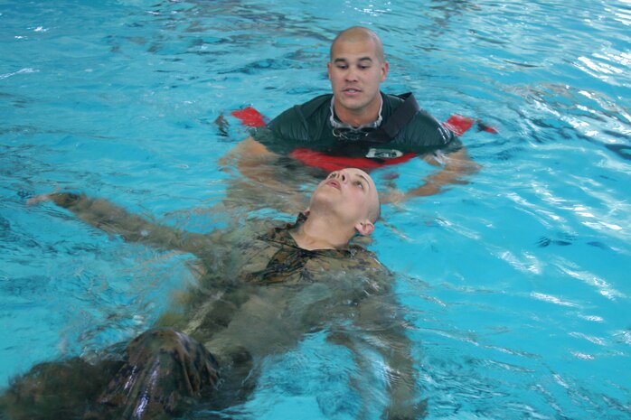 An instructor supervises a recruit of Company G, 2nd Recruit Training Battalion, as he learns to tread water May 22 at the swim tank aboard Marine Corps Recruit Depot San Diego. It is important that every recruit learns how to swim with combat utility uniforms as well as combat boots so they can understand how difficult it is to swim under these conditions. 