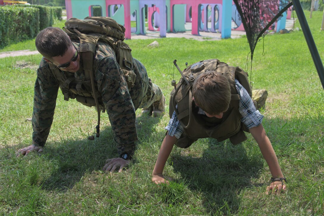Gunnery Sgt. Lee A. Nickel, a reconnaissance Marine with Black Sea Rotational Force 12and Detroit, Mich. native participates in a push up contest with a Romanian child at Tabacarie Park in Constanta, Romania June 2. The Marines and sailors of BSRF 12 participated in a weekend of volunteering in celebration of International Children’s Day. Throughout the weekend Marines volunteered in various events including a static display at a local park, playing with orphaned children and a park clean up.