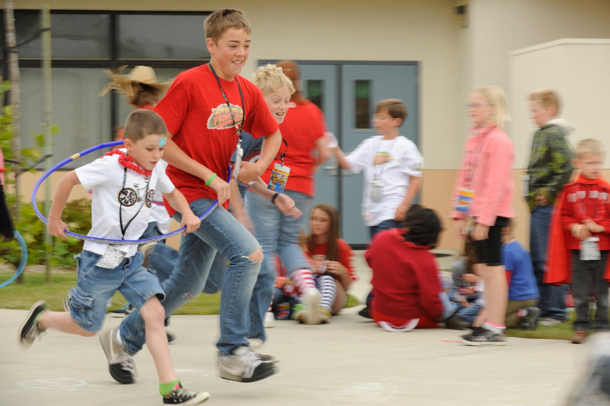 VANDENBERG AIR FORCE BASE, Calif. -- Elijah and Caleb Marshall, ages 11 and 13, run in a hula-hoop race at Vacation Bible School hosted by the 30th Space Wing Chapel staff here Friday, June 15, 2012. The school is in their tenth year of operation, teaching 140 students in five different classes with the help of more than 50 base volunteers. (U.S. Air Force photo/Staff Sgt. Levi Riendeau)
