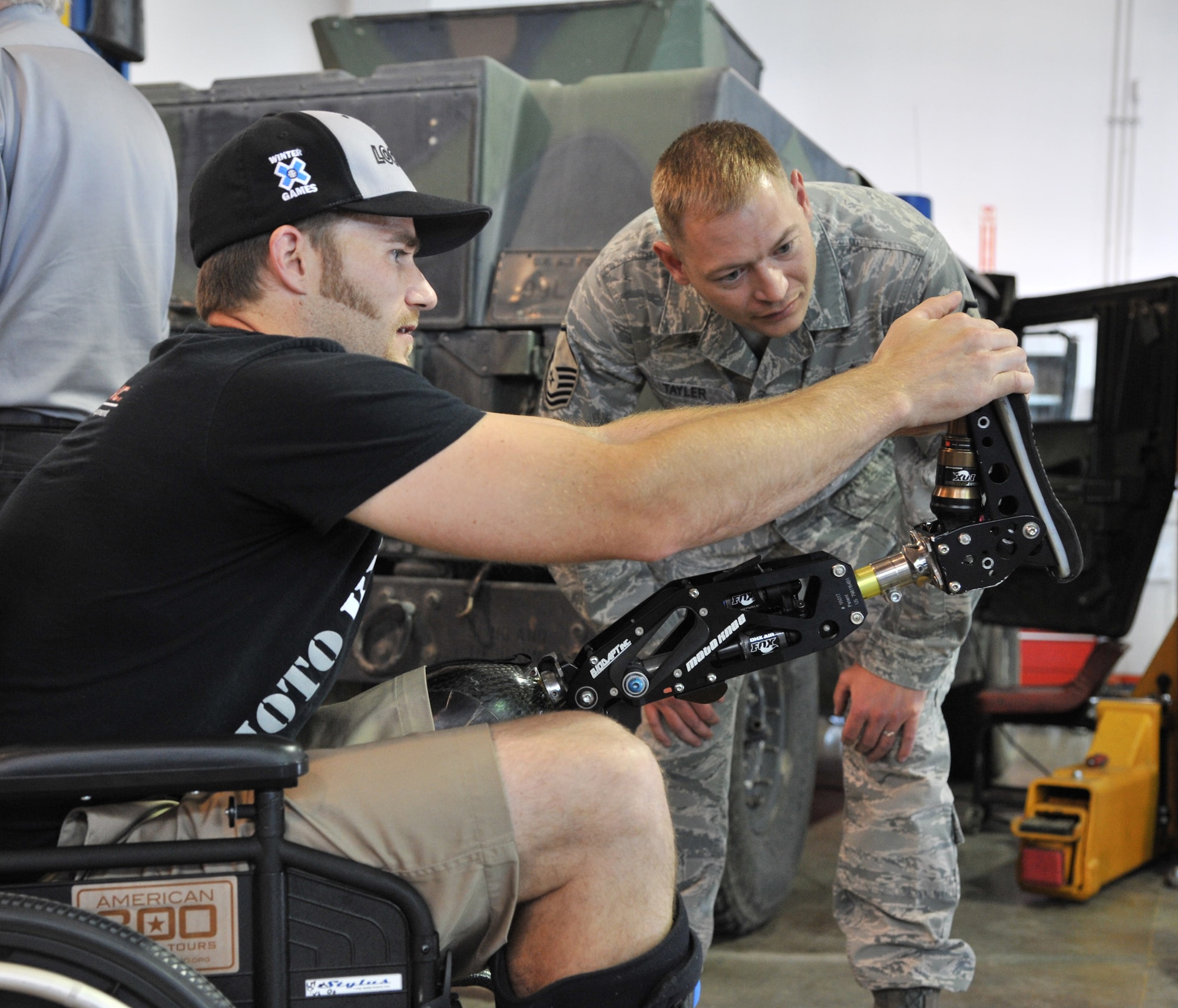 Mike Schultz explains the mechanics of his prosthetic leg and moto knee to Master Sgt. Justin Tayler, 341st Logistics Readiness Squadron vehicle fleet manager, when he was visiting them June 12 as part of the American300 Baja 1000 Tour. Schultz designed the prosthetic so he could continue to compete in both MotoX dirtbike and SnoX snowmobiling races. You can find out more about him at www.monstermikeschultz.com. (U.S. Air Force photo/John Turner)