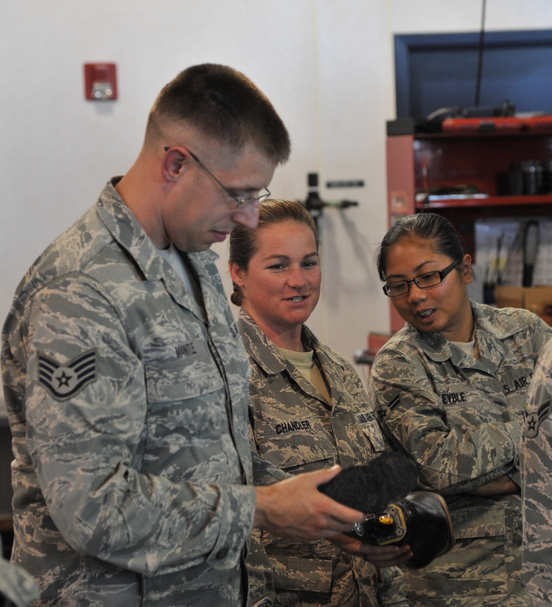Staff Sgt. Eric Mantle, Tech. Sgt. Shane Chandler and Airman 1st Class Marilou Leyble, all members of the 341st Logistics Readiness Squadron vehicle management and analysis fleet, inspect the competition prostetic that Chris Ridgeway uses. It is different from his daily-use prostetic. Ridgeway will be competing in the Baja 1000 Nov. 14-17. You can follow the team by going to www.jhchero.org. (U.S. Air Force photo/John Turner) 