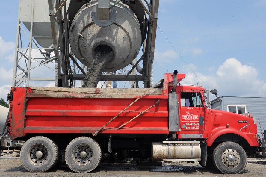 A construction worker waits as a cement mixer fills his truck with cement for runway construction on Seymour Johnson Air Force Base, N.C., June 13, 2012. After he receives the cement, he takes it to the runway and dumps it onto a conveyer belt so it can be evenly dispensed onto the runway. (U.S. Air Force photo/Airman 1st Class John Nieves Camacho/Released)