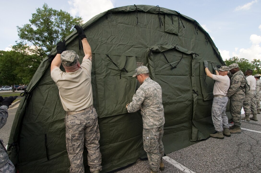 A group of 779th Medical Wing members secure an end cap on to the frame of a 25-bed field hospital during a disaster response exercise held at Joint Base Andrews, Md., on June 6. (photo/Bobby Jones)