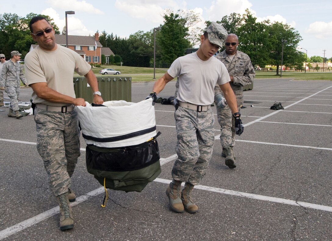 Maj. Benjamin Feliciano, 779th Medical Support Squadron disease manager, and Capt. Vinh Phung, 779 MDSS pharmacist, transport a tent door which serves as the end cap support of a 25-bed field hospital being constructed during a disaster response exercise conducted at Joint Base Andrews, Md., on June 6. (photo/Bobby Jones)