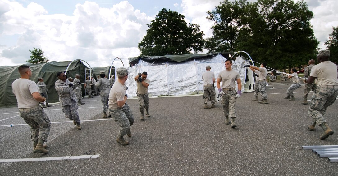 779th Medical Wing members pull on lines to drape a tent cover over a 25-bed field hospital during a disaster response exercise conducted at Joint Base Andrews, Md., June 6. The members were part of two Expeditionary Medical Support Teams who honed their skills constructing and dismantling the deployable field hospitals. The hospitals are designed to deliver limb and lifesaving capabilities to a contingency within 24-hours. (photo/Bobby Jones)
