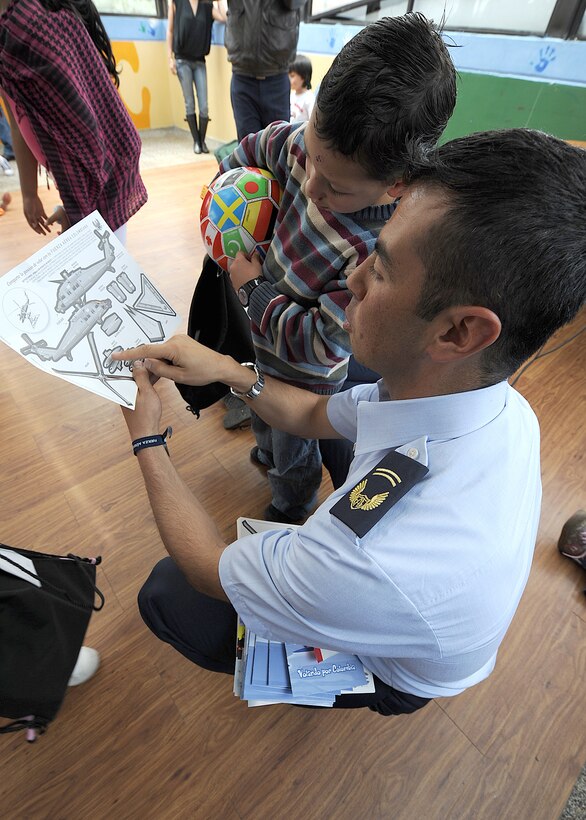 A member of the Colombian air force explains to a child from Asociación Amigos del Niño Ayudame, Bogota, Colombia how to put together a paper-model helicopter, as one of the donated items members of the Colombian air force and the 571st Mobility Support Advisory Squadron handed out during their visit to the orphanage June 9.  Airmen from both the Inter-American Air Forces Academy and 12th Air Force (Air Forces Southern) also participated in the visit.  (U.S. Air Force photo by Tech. Sgt. Lesley Waters)