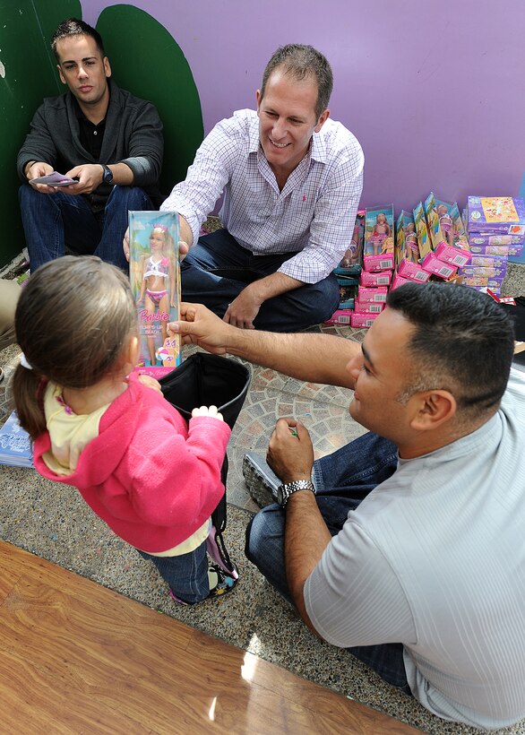 Staff Sgt. Angel Ortega, 571st Mobility Support Advisory Squadron air advisor, looks on as Lt. Col. Gabe Griess, 571st MSAS director of operations, and Master Sgt. Roberto Vasquez, 12th Air Force (Air Forces Southern), hand of the children at Asociación Amigos del Niño Ayudame, Bogota, Colombia, during their visit to the orphanage June 9, as part of an Air Mobility Command Building Partner Capacity month-long mission. (U.S. Air Force photo by Tech. Sgt. Lesley Waters)