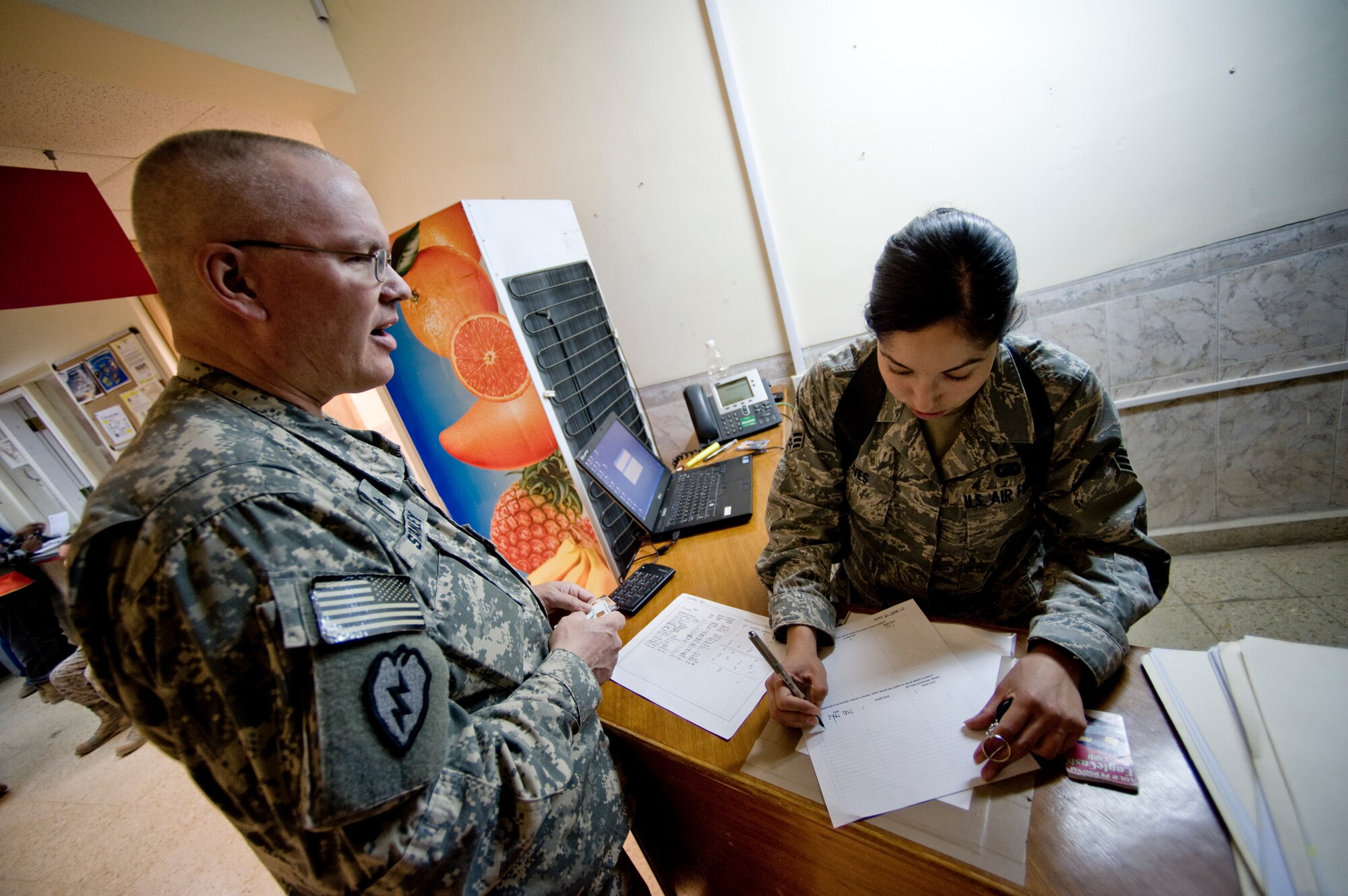 Senior Airman Deborah Vives with the Office of Security Cooperation - Iraq Financial Management team, assists a customer June 6 in Taji, Iraq. The OSC - I FM team travels to several sites in Iraq helping U.S. military personnel and civilian contractors with EagleCash and cash operations, setting up a new way to conduct financial services after the 2011 Armed Forces drawn down.  (U.S. Air Force photo by Staff Sgt. Greg C. Biondo)