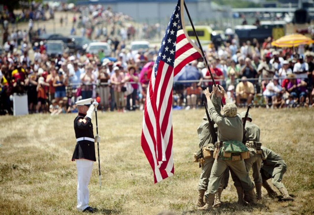 CLEVELAND-  The conductor of the Silent Drill Platoon salutes the American Flag ran out by the Marines as part of a flag rising on Iwo Jima during the Marine Air-Ground Task Force demonstration here, June 16, 2012. During the culminating event of Marine Week Cleveland, Marines will invaded the Burke Lakefront Airport by land, air, and sea. Gateway Plaza, Public Square, Voinovich Park, and Rock and Roll Hall of Fame are some of venues that displayed Marine Corps vehicles, aircraft and equipment during the week. Marine Week Cleveland celebrates community, country and the Corps. More than 750 Marines journeyed to Cleveland for the event. Ohio has more than 9,000 active and reserve Marines, making it one of the top-five producers of Marines. (U.S. Marine Corps Photo by Cpl. Marcin Platek)::r::::n::