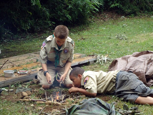 Scouts Ryan Archambault and Arzel Alexander work on their fire making skills for their wilderness survival badges during the Boy Scouts of America Summer Jamboree at Yokosuka Air Base Tama Hills recreation center June 17, 2012. There are more than 125 different types of merit badges for a scout to achieve.