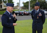 Col. Joe Dague, 15th Wing vice commander (right), listens as Col. Sam Barrett, 15th WG commander, speaks to Airmen from the 15th WG during Dague's Legion of Merit presentation ceremony June 15 at Joint Base Pearl Harbor-Hickam, Hawaii. The Legion of Merit decoration is presented to officers and enlisted men of the Armed Forces of the United States and on nationals of other counties who have distinguished themselves by exceptionally meritorious conduct in the performance of outstanding services and achievements.