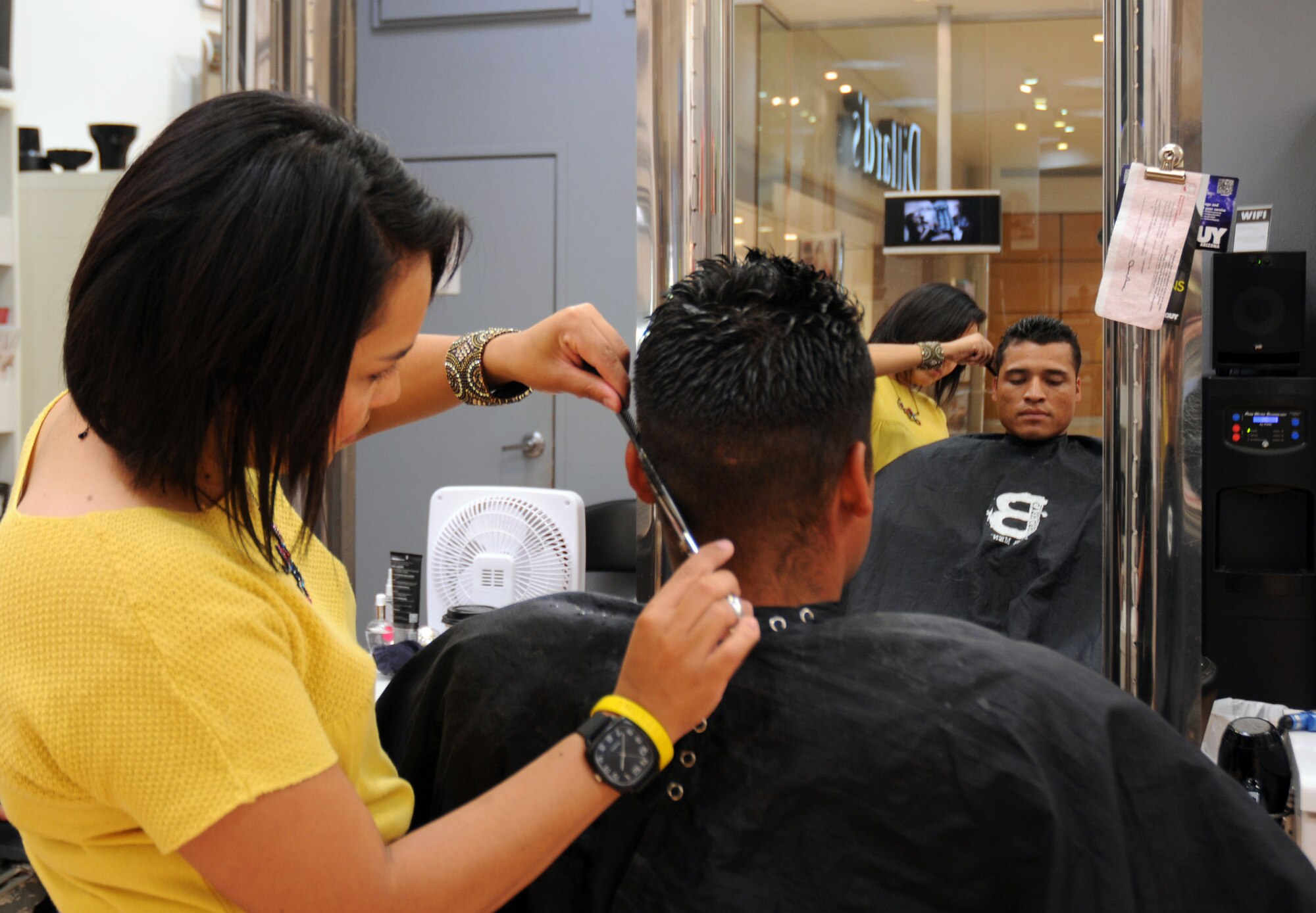Staff Sgt Kevin Semallie, 944th Civil Engineer Squadron, relaxes while he gets a haircut from stylist Ivonne Brand as part of Father’s Day event celebrating military dads. In a show of support for the military and their families three Phoenix area businesses teamed up to celebrate dads in uniform on Father’s Day. Toni and Guy Salon, Dillard’s Department Store, and Uptown Alley, an entertainment complex and full service restaurant, treated three Airmen to a special celebration Sunday. (U.S. Air Force photo/Capt. Elizabeth Magnusson)