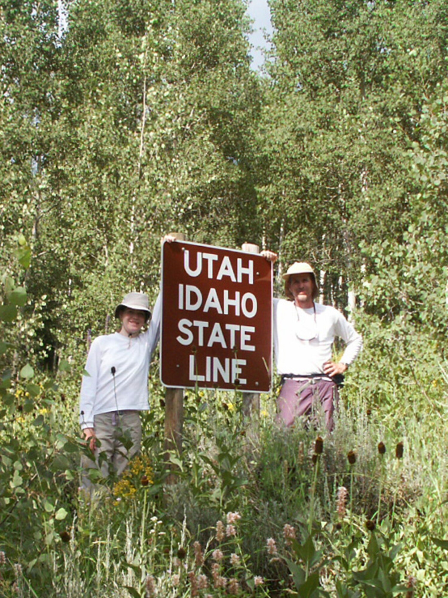Jette Carr and Jon Warnick stand next to the sign stating they had crossed the Utah-Idaho state line, finishing their walk across the state, summer of 2003. The hike was part of a trek spanning from the bottom to the top of Utah to each boarder – a journey that took 43 days and was nearly 700 miles long.  (Courtesy photo)