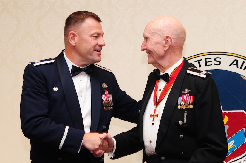 Retired Col. Gail Halvorsen, the famed "Candy Bomber," shakes hands with Col. Richard McComb, Joint Base Charleston commander, during the Airman Leadership School graduation, at Joint Base Charleston, S.C., June 14, 2012.  Halvorsen was a command pilot in the United States Air Force. He is best known for piloting C-47s and C-54s during the Berlin Airlift from 1948-1949. Halvorsen dropped candy attached to parachutes to children below. His main goal was to raise the morale of the children during the time of uncertainty. (U.S. Air Force photo/ Airman 1st Class Chacarra Walker)